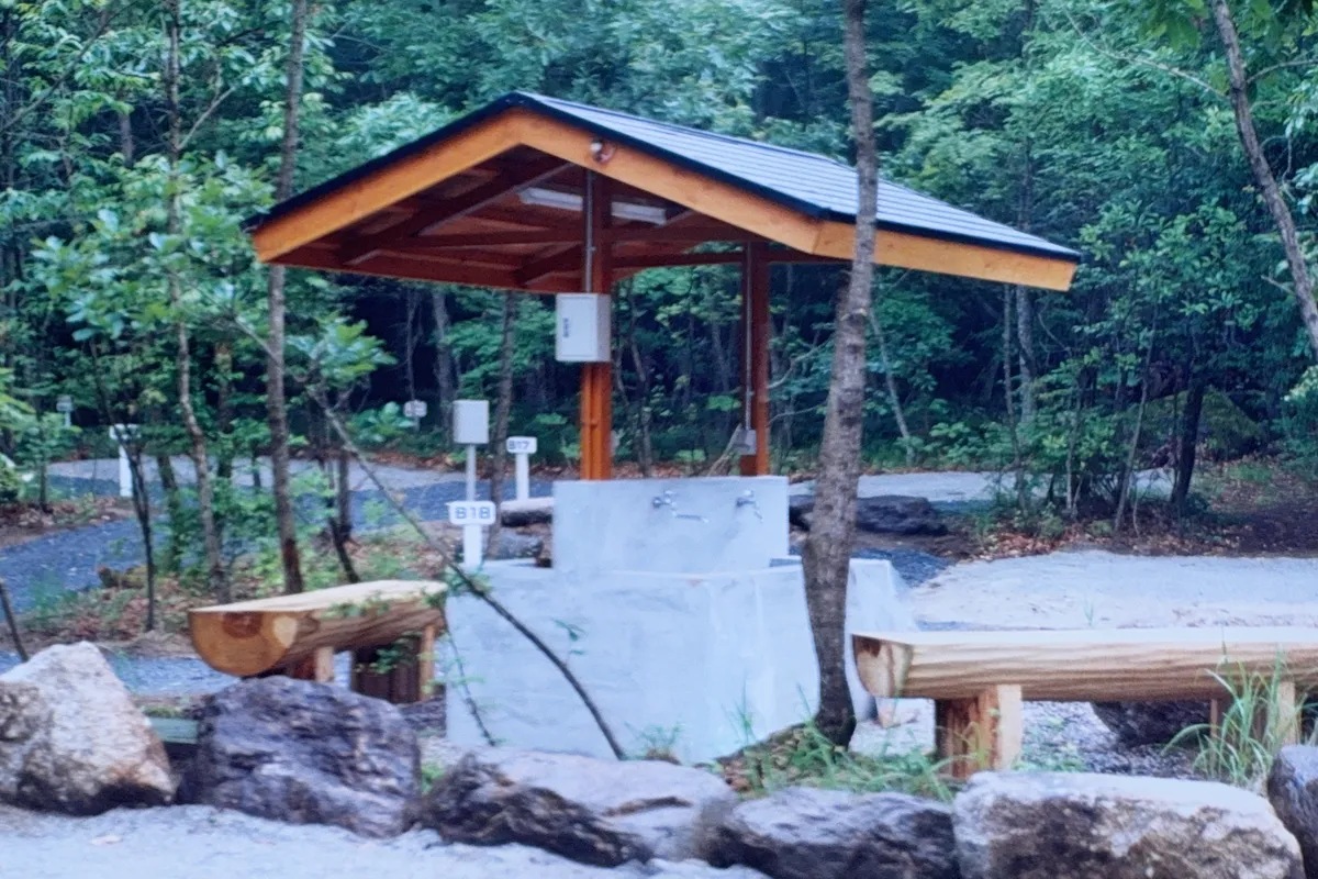 屋根付きの炊事場には水道と丸太のベンチが設置されている