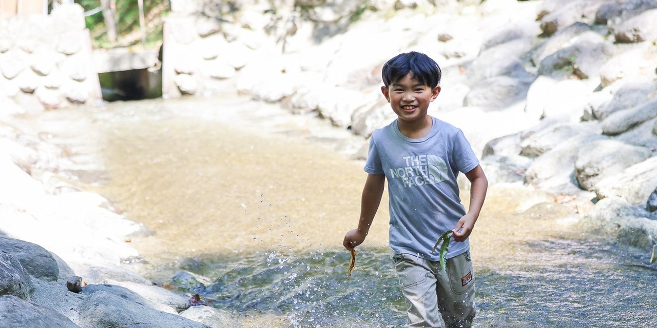 川の中を駆けて水しぶきをあげる子ども